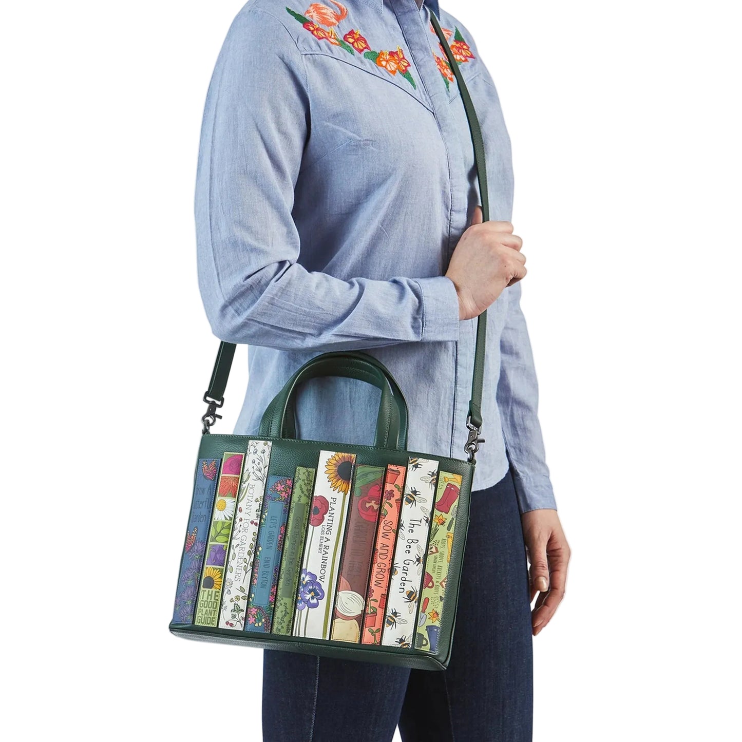 Person holding a green handbag with book design on a white background